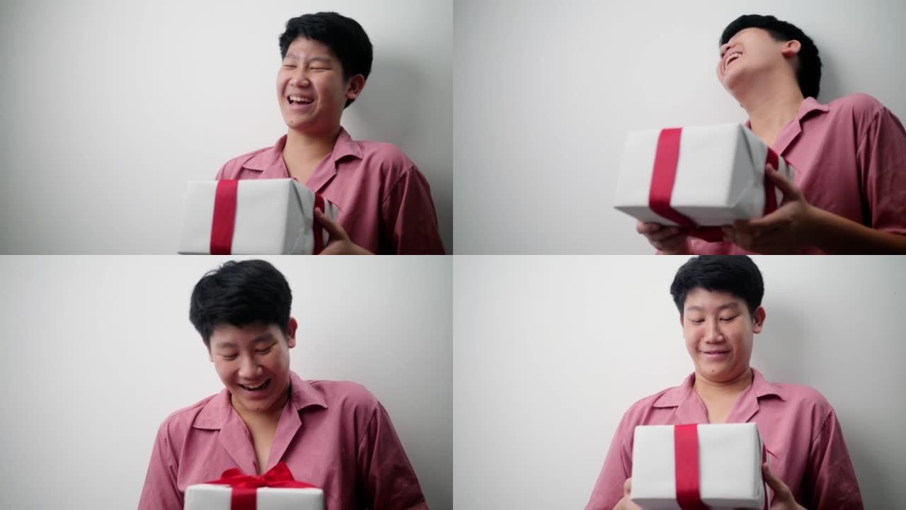 快乐的亚洲少年男孩手里拿着红色丝带的白色礼品盒，节日生活理念。