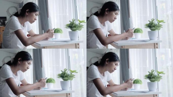 亚洲少女在家通过窗户附近的智能手机观看病毒视频或电影，生活方式概念。