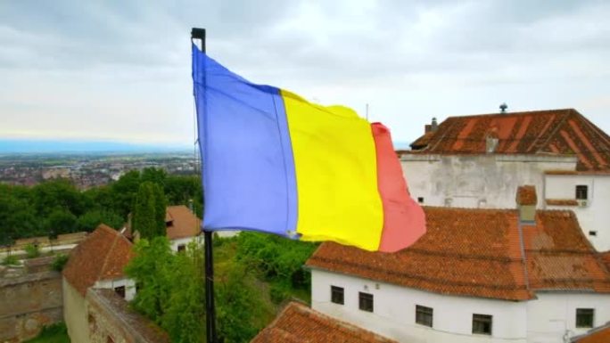 罗马尼亚布拉索夫城堡的空中无人机视图。中世纪的堡垒和国旗在山顶上。周围的建筑物和绿树