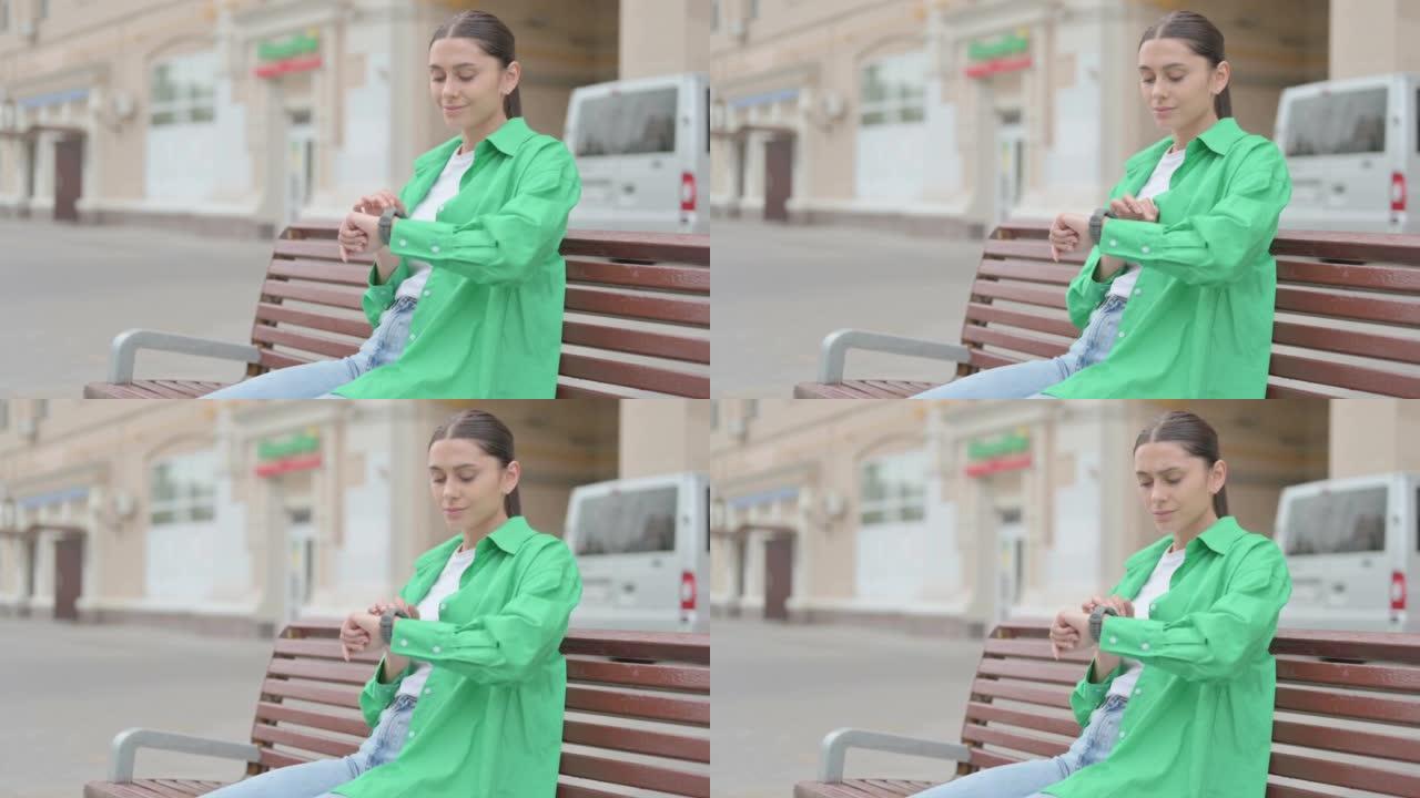 Hispanic Woman Using Smart watch while Sitting on 