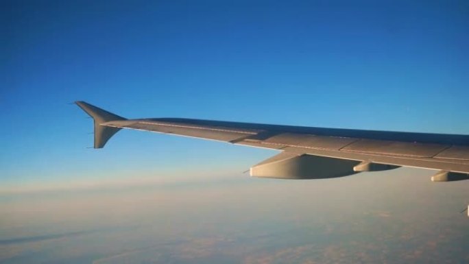 飞机机翼的一部分穿过窗户，靠着蓝色的夜空，云彩。