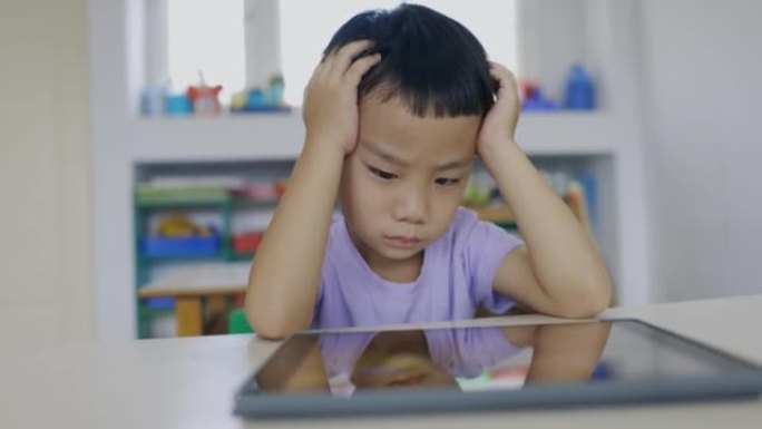 亚洲小男孩使用数字平板电脑观看