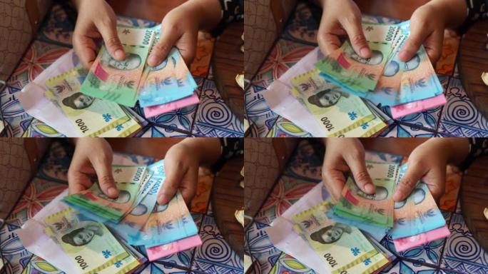 A woman is counting rupiah banknotes