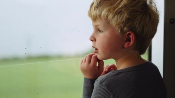 小男孩从火车窗外望着路过的乡村
