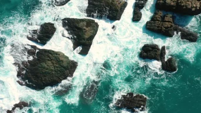 空中俯视图4k镜头由海洋蓝浪无人机在落基山的高崖上断裂。海滩上的危险海浪
