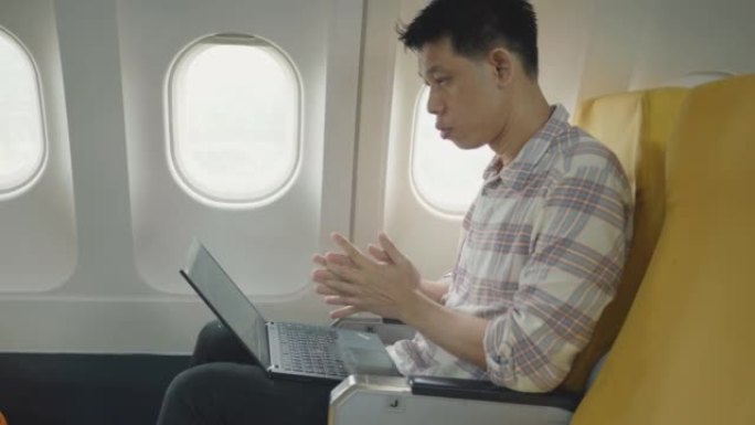 乘飞机旅行时使用笔记本电脑和手机的东南亚商务旅客。