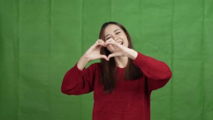 快乐的亚洲女人穿着红色毛衣，在绿色背景上爱自己的概念孤立。
