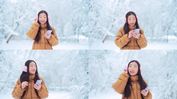 快乐开朗有趣的亚洲少女女学生在白雪皑皑的冬天在公园里听音乐。拥有手机智能手机的年轻女子喜欢在寒冷的天