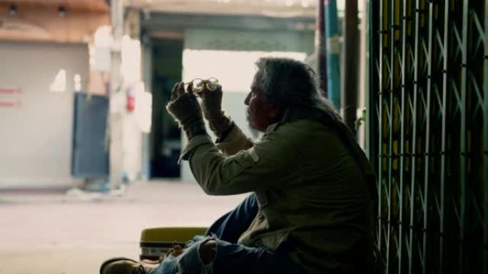 乞丐无家可归的老人心烦意乱，坐在人行道上没钱，失业的可怜的老人试图修理他的破眼镜，社会经济问题人权利