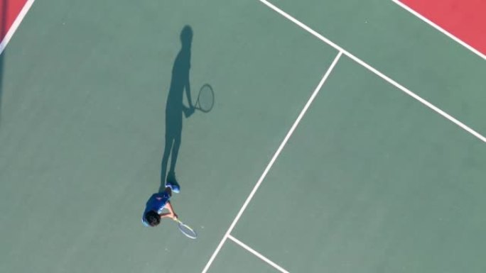 正下方无人机视点亚洲华裔职业网球选手上午在网球场练习