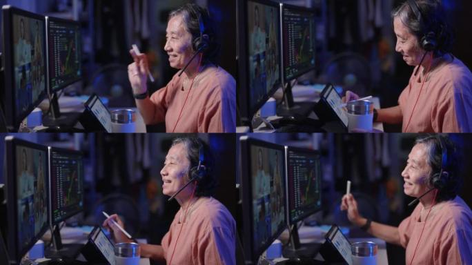 退休亚洲高级女性戴耳机晚上坐在电脑前学习加密股票市场交流在线导师培训课程在家通过视频电话会议