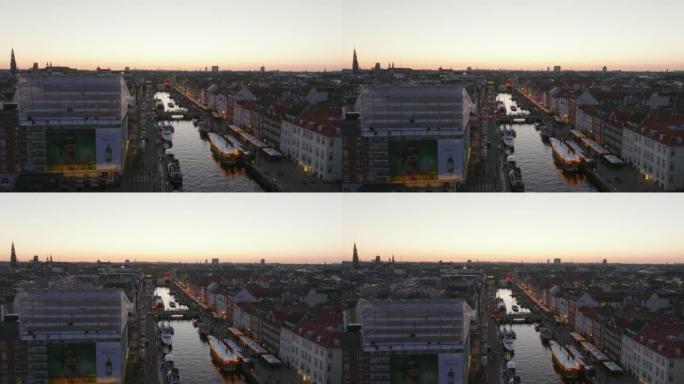 Nyhavn的空中上升镜头。有水渠和长廊的著名街道。水面反射着黄昏的天空。丹麦哥本哈根