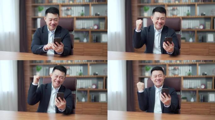 快乐成熟的亚洲商人在办公室用情感看着手机赢家或赢家，金融股体育博彩。男性高兴地惊呼玩游戏。