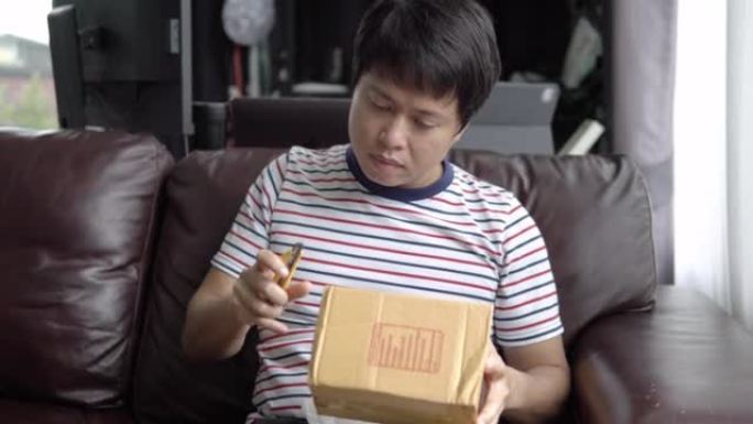 亚洲男子从网上商店切盒子。