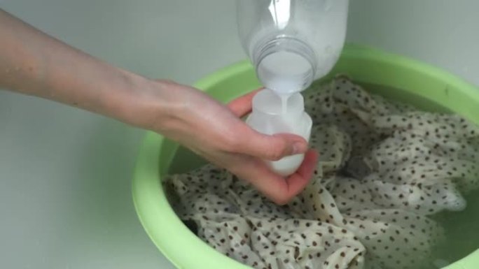 女人正在用手在盆子里用精致的织物冲洗衣服。