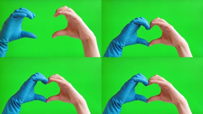 双手在绿色屏幕背景上孤立的心脏形式的医用手套。特写。人手制作心形手势隔离在色度键屏幕上。人用手指形成