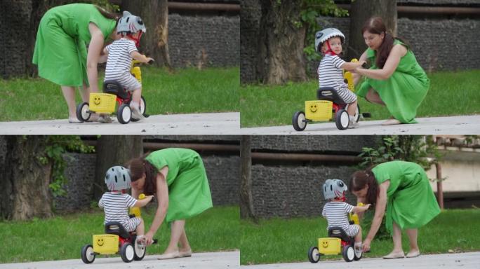 Mother teaching little child to ride tricycle for 