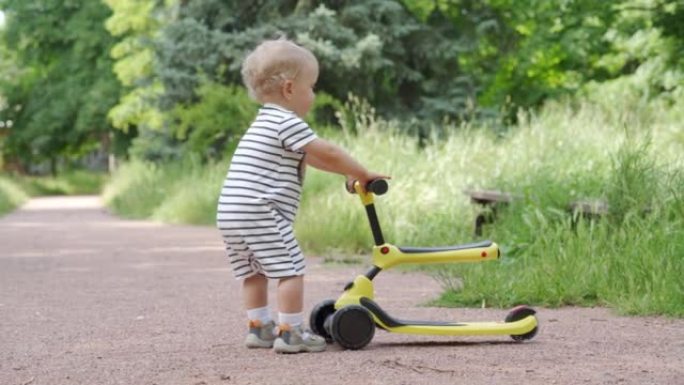 快乐的孩子在户外学习为年幼的孩子骑平衡自行车，1.5岁的孩子在夏天在公园里为幼儿玩脚踏车。