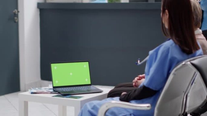 亚洲护士和患者正在看带有绿色屏幕的笔记本电脑