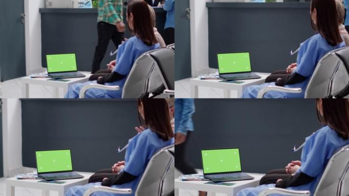 亚洲护士和患者正在看带有绿色屏幕的笔记本电脑