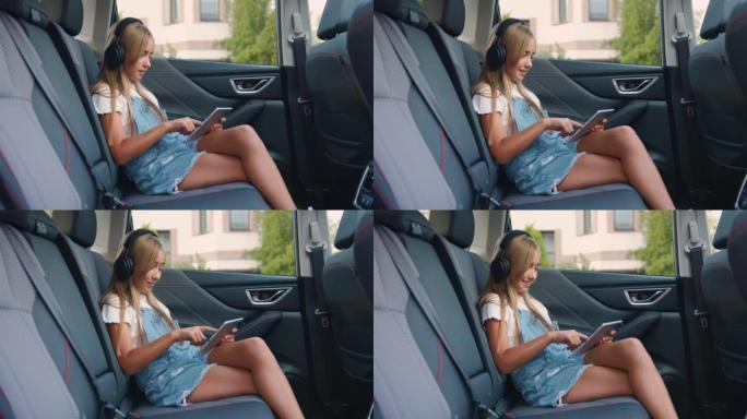 漂亮微笑的白人女孩，平板电脑坐在车里。车载阅读数字平板电脑中的女孩乘客