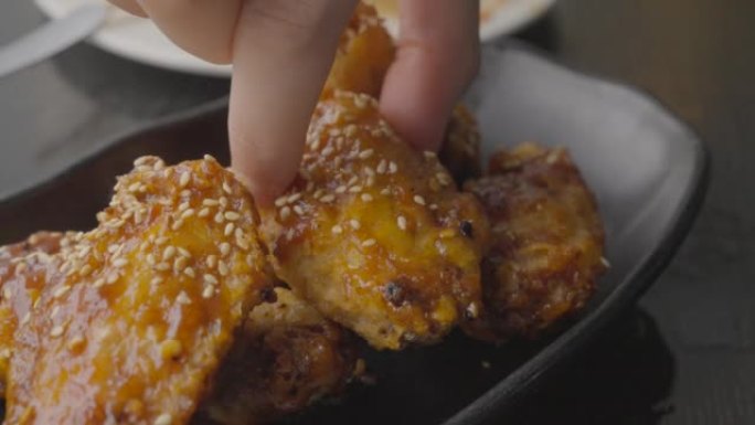 hand picks up sweet sticky chicken wings close up