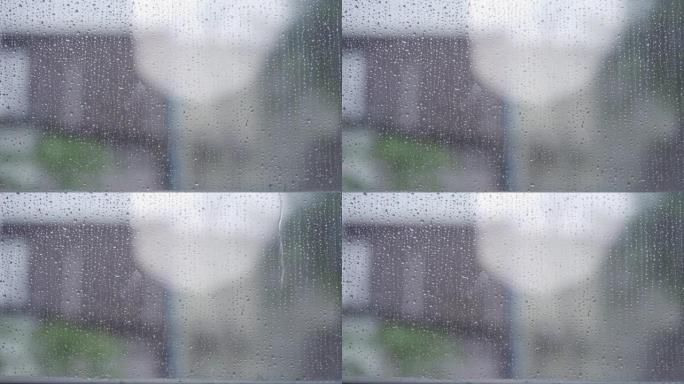 雨滴从玻璃窗格流下的特写镜头背景模糊的玻璃窗上的雨滴