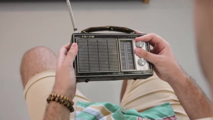 男子在便携式老式收音机上寻找电台并调节音量