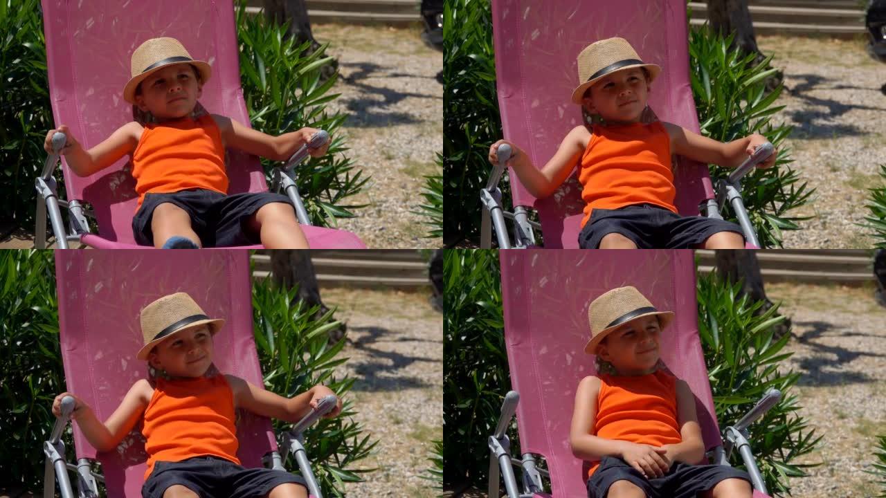 戴着草帽的开朗男孩躺在粉红色的躺椅上，仰望天空