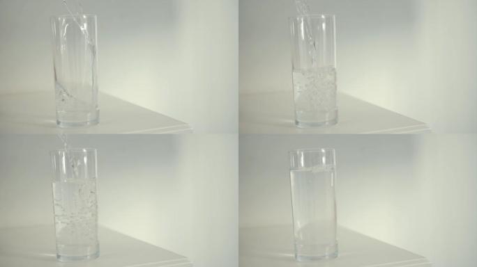 工作室拍摄的水倒入白色背景的透明玻璃中。