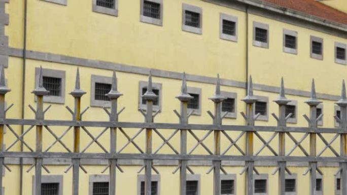 带有旧历史监狱建筑尖刺的金属栅栏，带有禁止的窗户