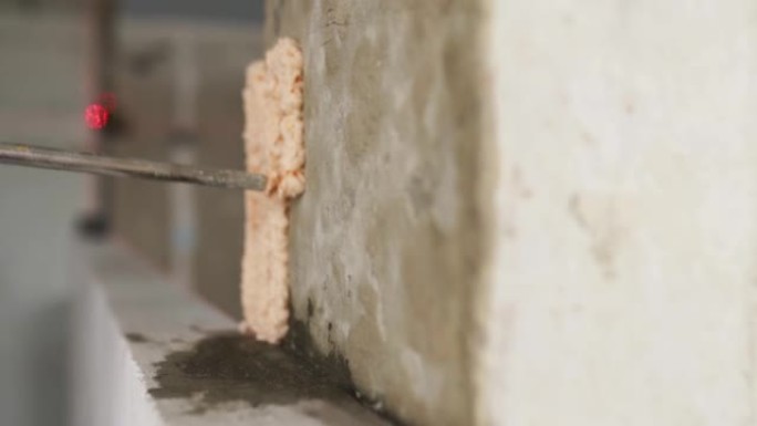 承包商在混凝土墙上使用带有喷枪的聚氨酯泡沫粘合剂来粘合蒸压加气混凝土砖。工人喷洒聚氨酯泡沫。孤立视图