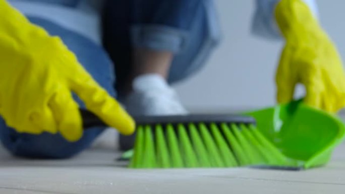 女人从地板上扫白灰到簸箕，清洁服务，特写