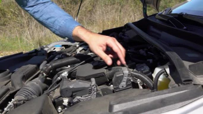 男子打开引擎盖并检查发动机问题，试图修复汽车故障