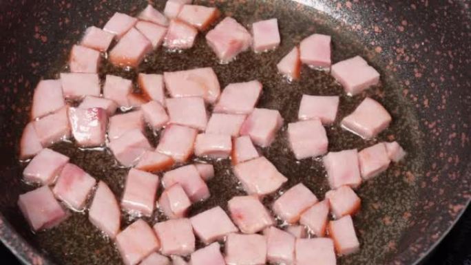 厨房刮刀在煎锅中用油搅拌培根或火腿。炉子上锅里的肉嘶嘶作响。烹饪猪肉。炒饭食谱的配料。食物和烹饪概念