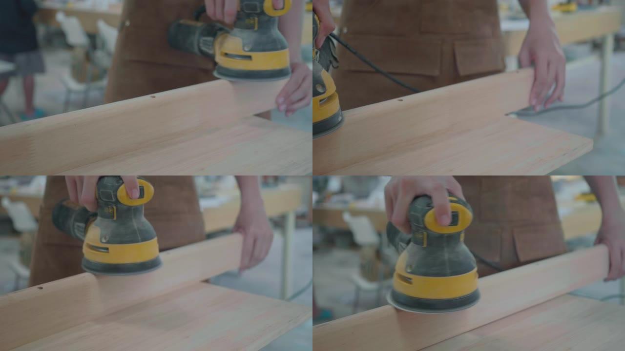 慢动作近距离拍摄一只手持圆盘砂光机的男性手的多莉镜头，并使车间的木板表面光滑。