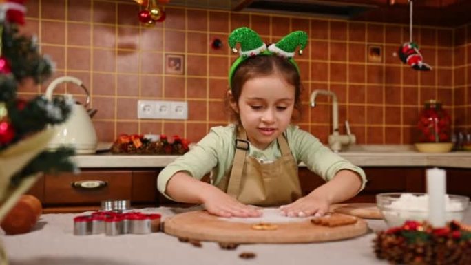 可爱的小孩在厨师的围裙和精灵箍上撒面粉在木板上，为姜饼饼干准备面团