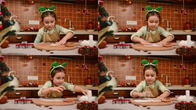 可爱的小孩在厨师的围裙和精灵箍上撒面粉在木板上，为姜饼饼干准备面团