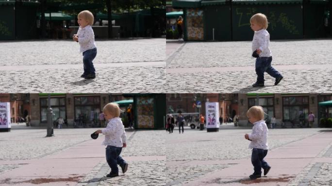 蹒跚学步的男婴带着刚发现的塑料帽垃圾在城市里行走