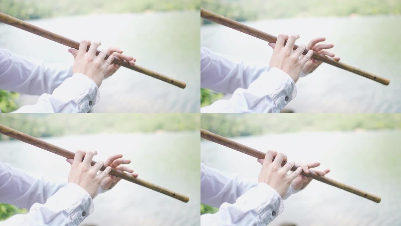 男性音乐家在演奏旋律时在传统木笛上关闭和打开孔