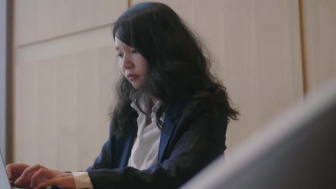 年轻的亚洲女子正在键盘上打字，并使用笔记本触控板。