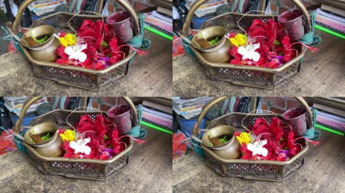 在一个小的金属篮子里近距离拍摄芙蓉花，里面有一个小的金属玻璃和一个金属卡拉什在Kalighat祈祷。