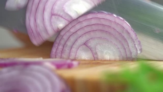 宏观拍摄手在厨房蔬菜背景的砧板上切新鲜的红洋葱。剁碎。