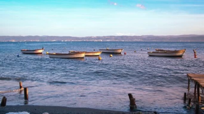 夏日日落时，渔船在海边的海浪上摇摆