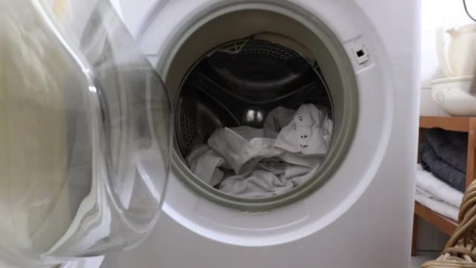女性的手将脏衣服与要洗的洗涤剂一起放入洗衣机