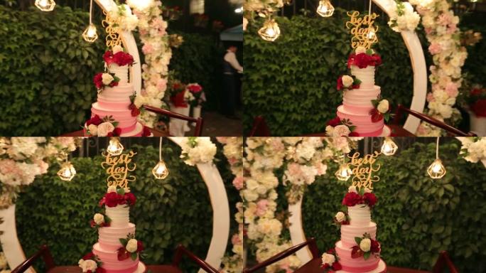 婚礼蛋糕，有史以来最好的一天在绿色花园上签名，为晚上的婚礼派对装饰。白色和玛萨拉创意装饰，圆形婚礼拱