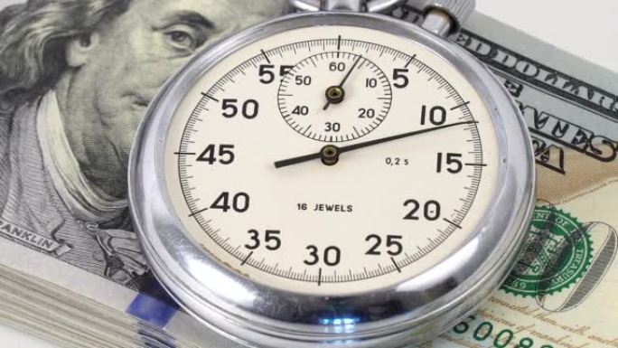 时间就是金钱概念。宏观。秒表以金钱为背景。美元纸币上的模拟金属秒表。时间就是金钱的概念，模拟秒表在带