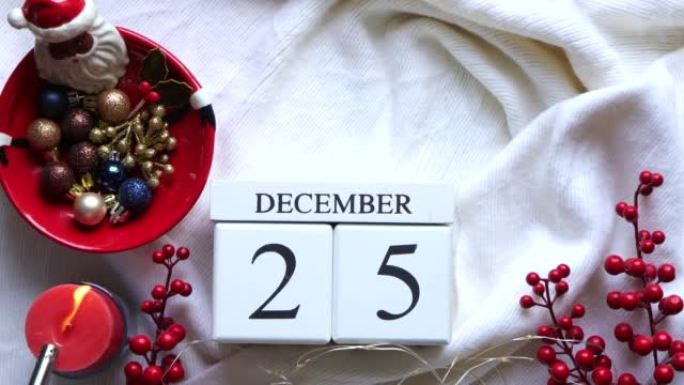 日历，带有12月25日日期和红色蜡烛，红色浆果，白色针织面料上的圣诞节装饰。圣诞节和新年快乐的概念。