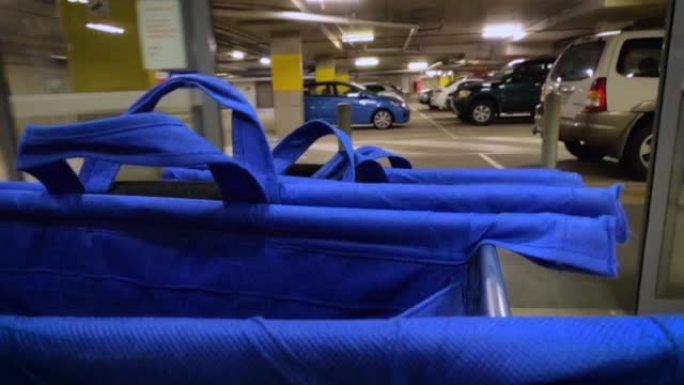 带有蓝色杂货袋的购物车沿着自动人行道进入车库。