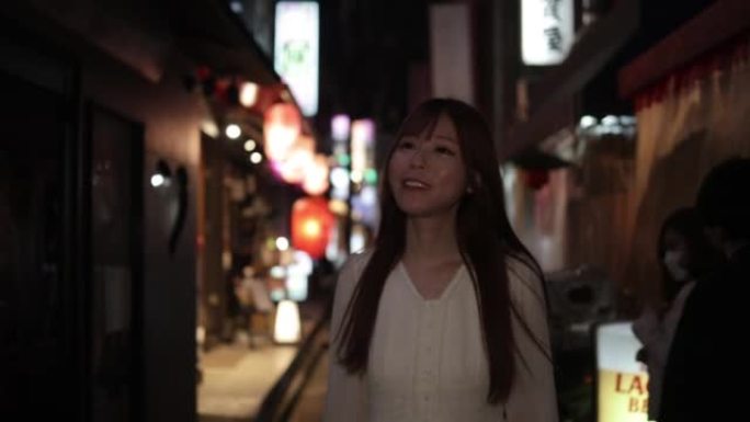 年轻女子晚上走在日本的 “izakaya” 街上
